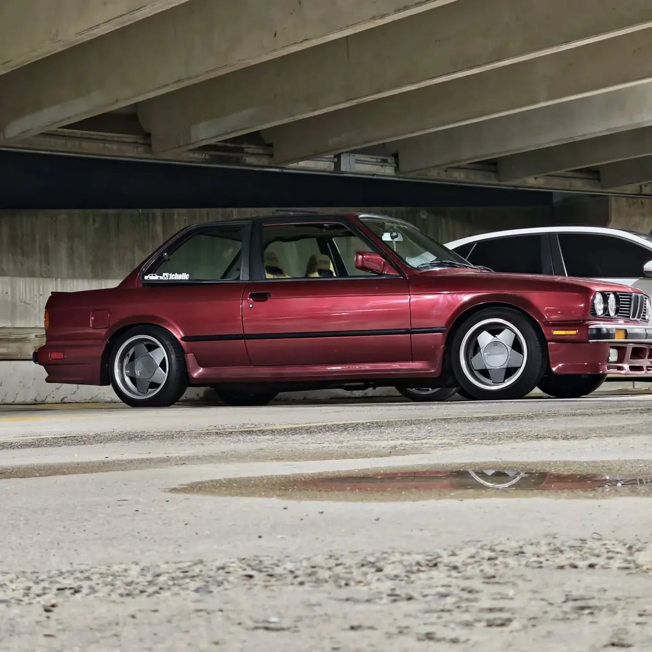 The burgundy E30 in profile on multi-spoke wheels