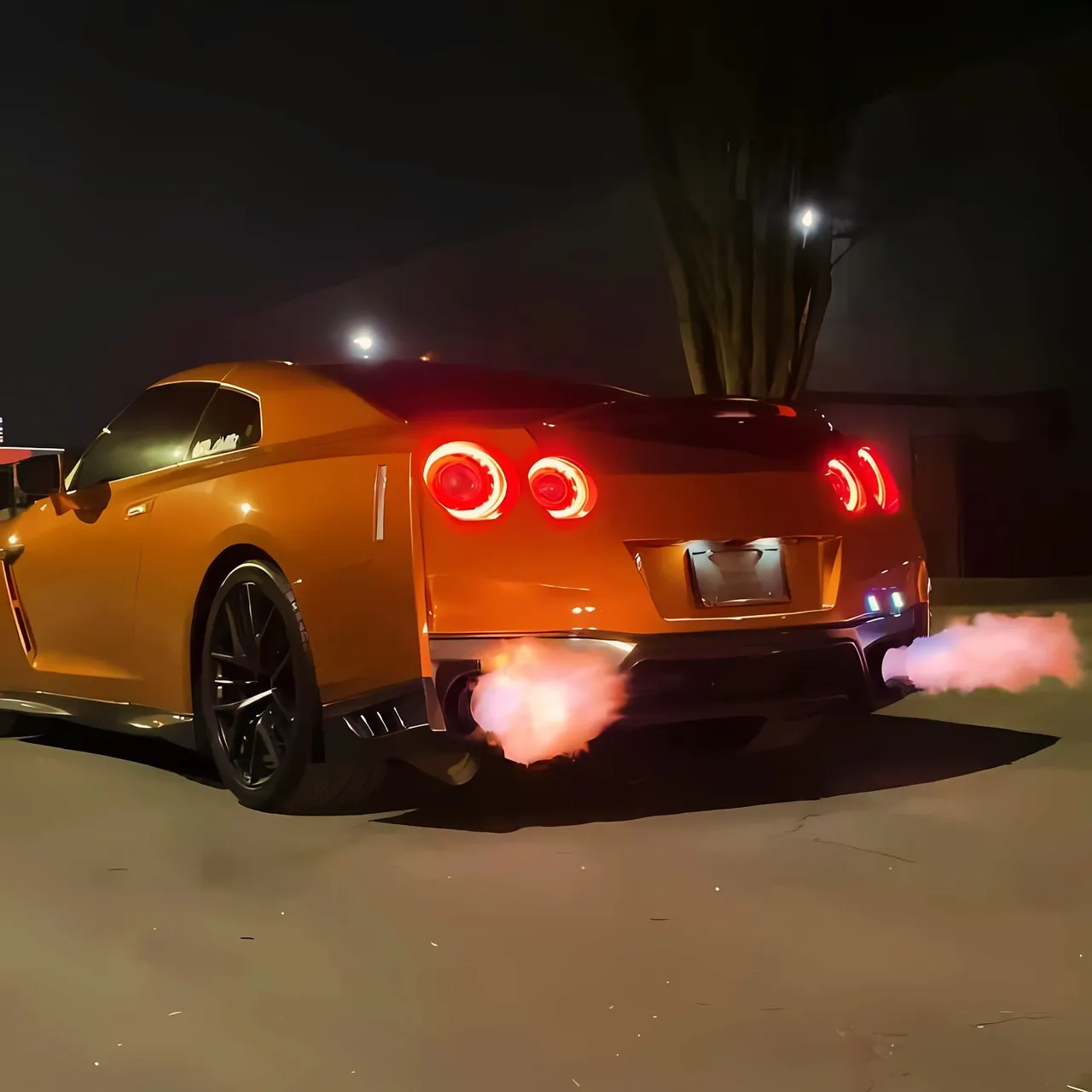The orange GT-R from behind at night, flames from the exhaust